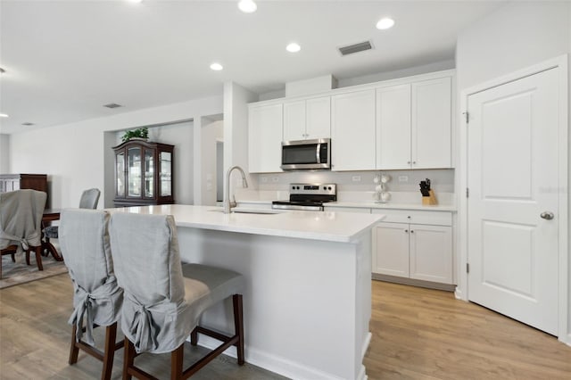 kitchen featuring white cabinets, light wood-type flooring, stainless steel appliances, and sink