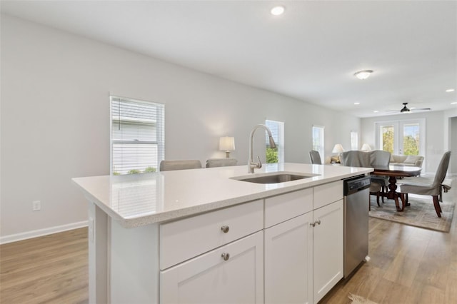 kitchen with sink, stainless steel dishwasher, an island with sink, light hardwood / wood-style flooring, and white cabinets