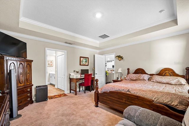 carpeted bedroom with crown molding, a tray ceiling, and ensuite bath