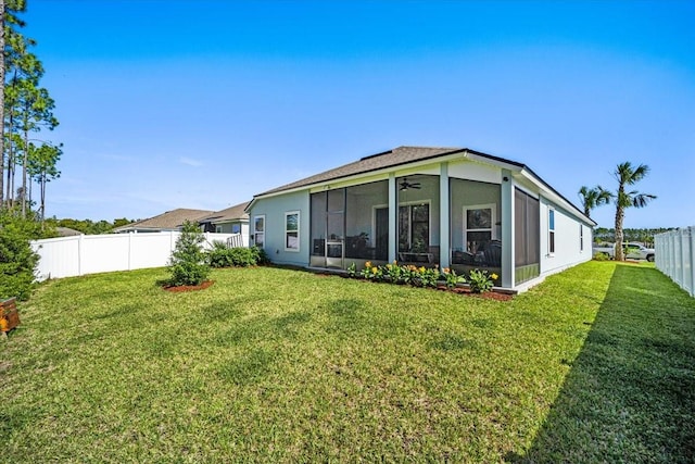 rear view of house with ceiling fan, a lawn, and a sunroom