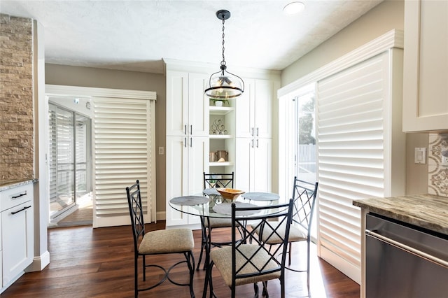 dining area featuring dark wood-type flooring, a textured ceiling, and an inviting chandelier