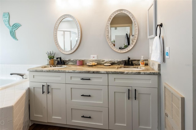 bathroom featuring hardwood / wood-style floors, vanity, and a relaxing tiled tub