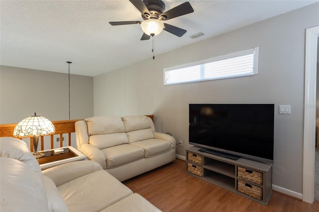 living room with ceiling fan, wood-type flooring, and a textured ceiling