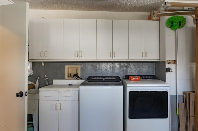 laundry room featuring a textured ceiling, washing machine and dryer, and cabinets