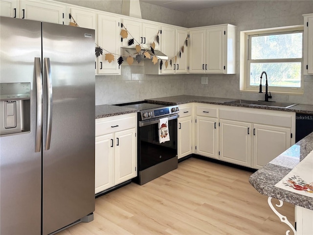 kitchen with white cabinetry, sink, light hardwood / wood-style floors, decorative backsplash, and appliances with stainless steel finishes