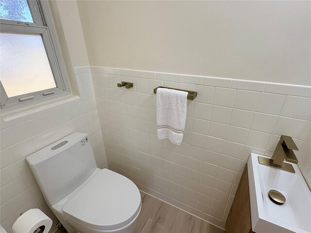 bathroom with wood-type flooring, toilet, and tile walls