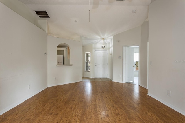 empty room featuring lofted ceiling, wood-type flooring, and plenty of natural light