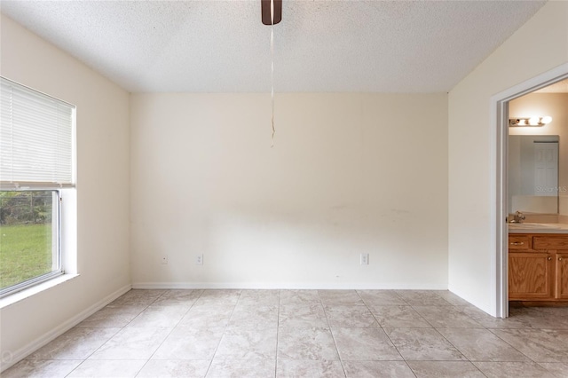 spare room with sink, a textured ceiling, light tile patterned floors, and ceiling fan