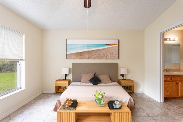 bedroom with a textured ceiling, ensuite bath, ceiling fan, and light tile patterned floors