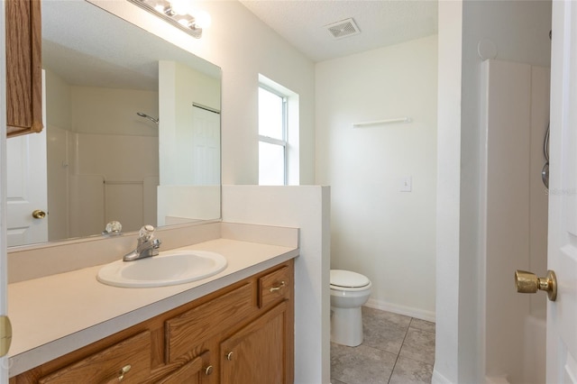 bathroom featuring vanity, a textured ceiling, tile patterned flooring, toilet, and a shower