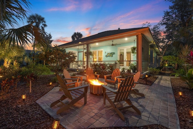 patio terrace at dusk featuring a fire pit and ceiling fan