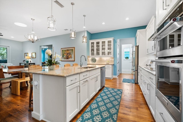 kitchen featuring an island with sink, a breakfast bar, white cabinetry, and light hardwood / wood-style flooring