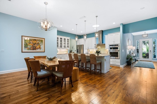 dining area featuring dark wood-type flooring, sink, and a notable chandelier