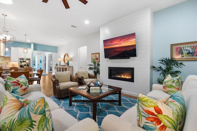 living room featuring a fireplace, hardwood / wood-style flooring, ceiling fan, and sink