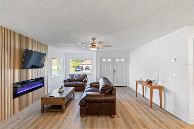 living room featuring ceiling fan, a textured ceiling, and light wood-type flooring