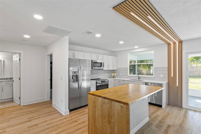 kitchen featuring appliances with stainless steel finishes, sink, a center island, light hardwood / wood-style floors, and white cabinetry