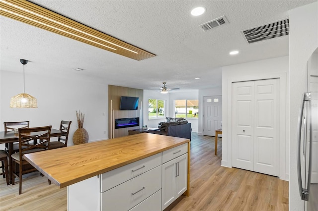 kitchen featuring white cabinets, ceiling fan, decorative light fixtures, light hardwood / wood-style floors, and butcher block counters