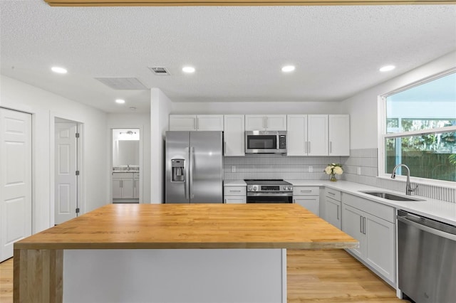 kitchen with stainless steel appliances, a kitchen island, butcher block counters, and sink