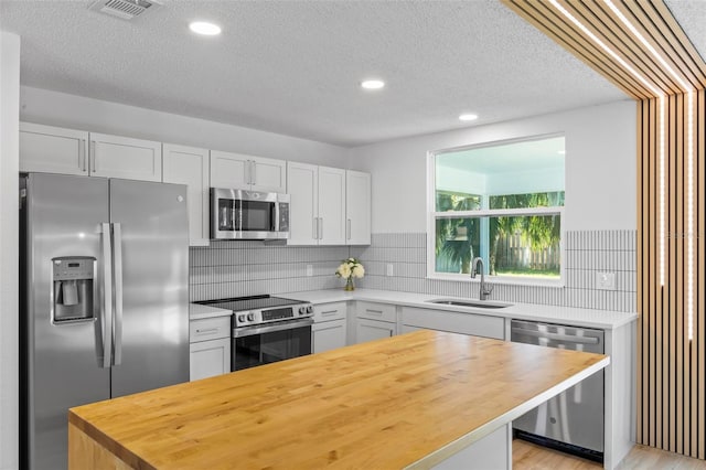 kitchen with white cabinets, appliances with stainless steel finishes, tasteful backsplash, and sink