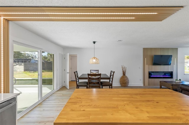 dining area featuring a large fireplace, light wood-type flooring, and a textured ceiling