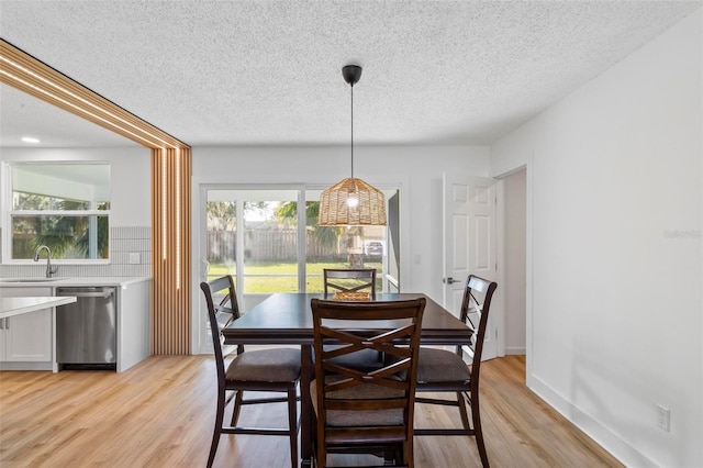 dining space with sink, a textured ceiling, and light hardwood / wood-style flooring