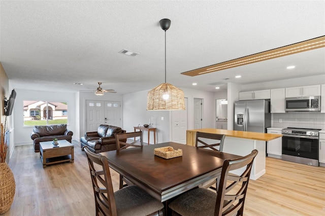 dining area with a textured ceiling, light hardwood / wood-style flooring, and ceiling fan