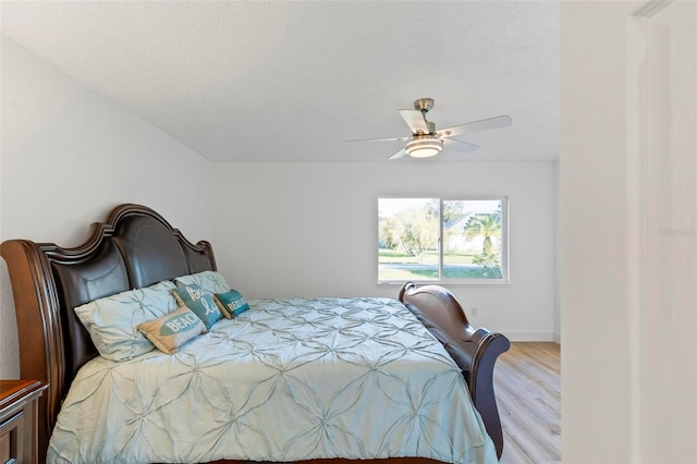 bedroom featuring ceiling fan, light wood-type flooring, and a textured ceiling