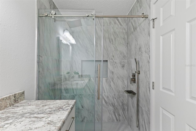 bathroom featuring vanity, a textured ceiling, and a shower with door