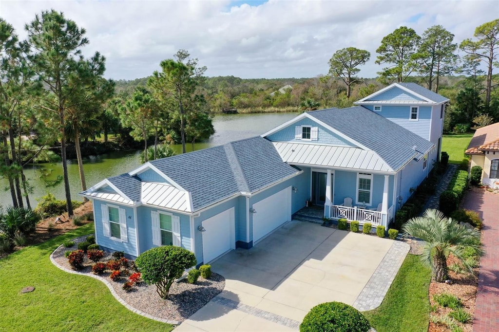 view of front facade with a front lawn, a garage, a water view, and covered porch