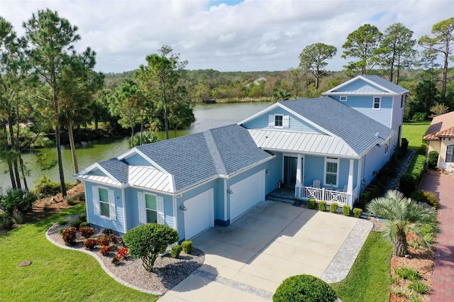 view of front facade with a front lawn, a garage, a water view, and covered porch