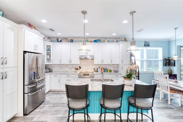 kitchen with ornamental molding, appliances with stainless steel finishes, decorative light fixtures, sink, and a kitchen island with sink