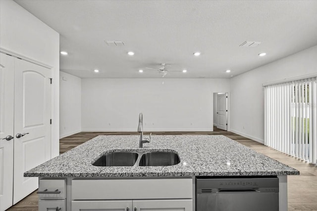 kitchen with light stone counters, sink, a kitchen island with sink, and dishwasher