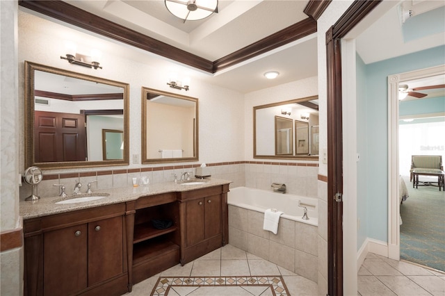 bathroom featuring tiled tub, ornamental molding, vanity, ceiling fan, and a raised ceiling