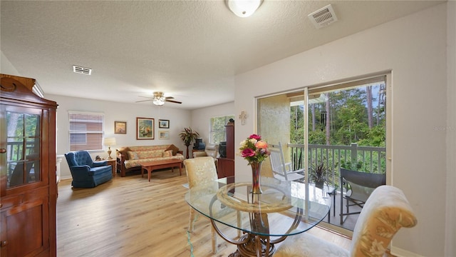 dining space with ceiling fan, a textured ceiling, and light hardwood / wood-style floors