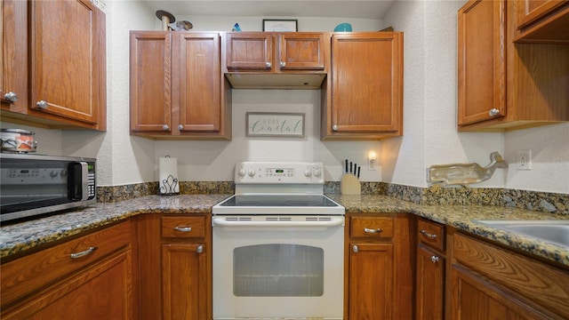 kitchen with dark stone counters, sink, and white range with electric stovetop