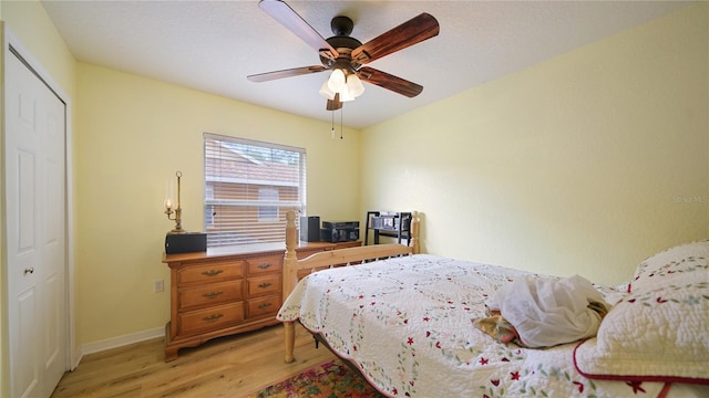 bedroom with light hardwood / wood-style flooring, ceiling fan, and a closet