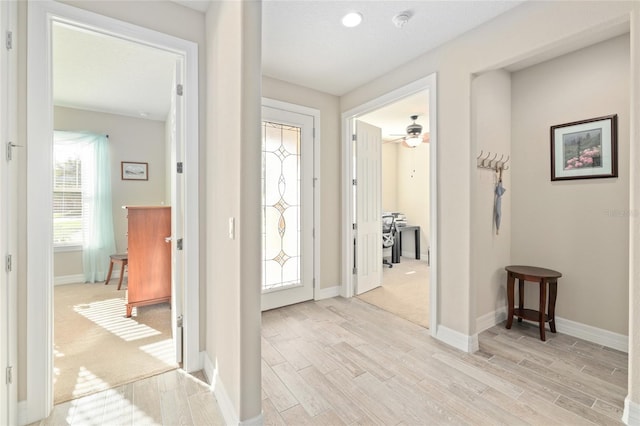 foyer entrance featuring ceiling fan, light wood-type flooring, and baseboards