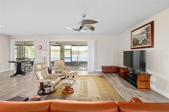 living area with a ceiling fan, baseboards, and wood finished floors