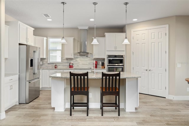 kitchen featuring wall chimney exhaust hood, visible vents, appliances with stainless steel finishes, and white cabinets