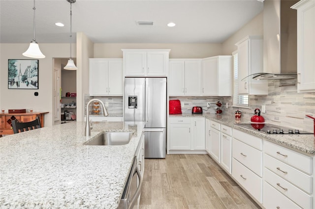 kitchen featuring visible vents, light wood-style flooring, appliances with stainless steel finishes, wall chimney range hood, and a sink