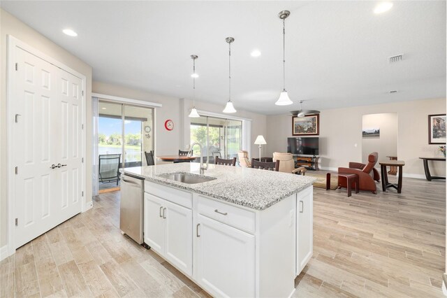 kitchen with visible vents, an island with sink, stainless steel dishwasher, light wood-style floors, and a sink