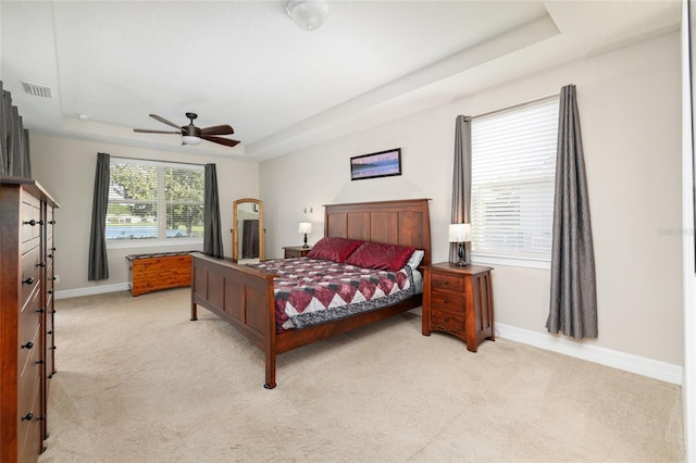 bedroom with carpet floors, a tray ceiling, visible vents, and baseboards