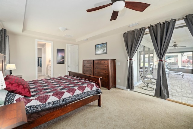 bedroom with carpet floors, visible vents, access to outside, a raised ceiling, and ensuite bath