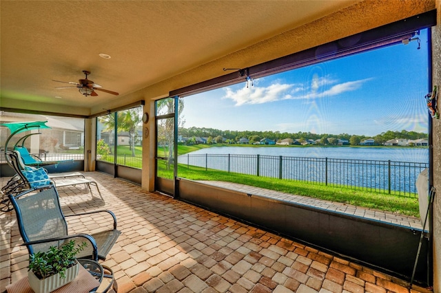 unfurnished sunroom featuring ceiling fan and a water view