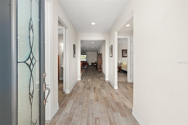 hall featuring recessed lighting, baseboards, and light wood finished floors