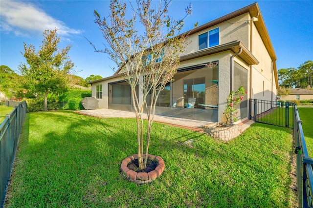 back of house with a fenced backyard, a yard, a gate, stucco siding, and a patio area