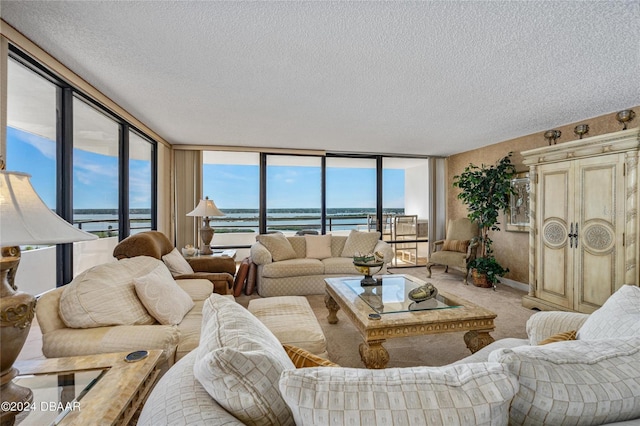 carpeted living room with expansive windows, a water view, and a textured ceiling