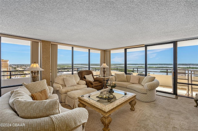 living room featuring expansive windows, a water view, a textured ceiling, and carpet flooring