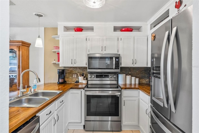 kitchen with wooden counters, sink, pendant lighting, and appliances with stainless steel finishes