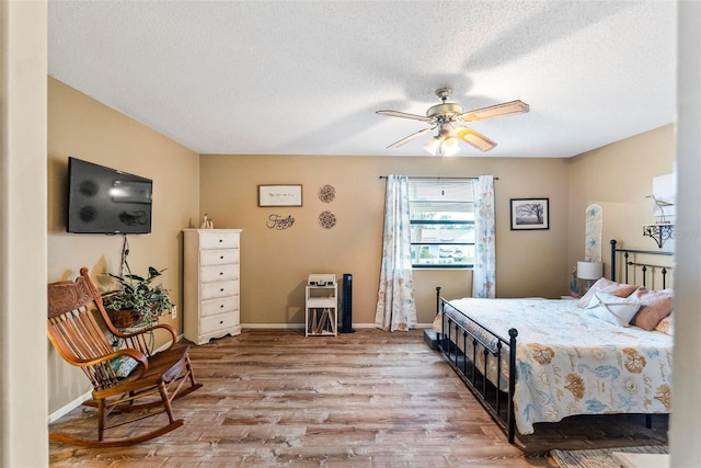 bedroom with a textured ceiling, ceiling fan, and light hardwood / wood-style flooring